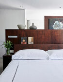 Bed with dark wooden partition headboard in bedroom