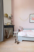 Pale grey bed and disused fireplace in girl's bedroom with pink wall