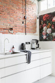 Whit fitted kitchen with exposed brick wall