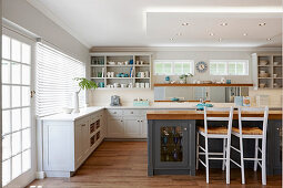 Grey-painted island counter with base cabinets and wooden worksurface in white fitted kitchen