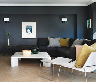 Black sofa in living room with black walls and parquet floor