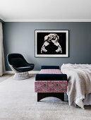 Upholstered armchairs, daybed at the end of the bed and large-format photography on a gray wall in the bedroom