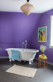 Free-standing bathtub below sloping ceiling in purple bathroom