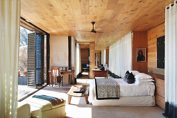 Doppelbett im Schlafzimmer mit Holzverkleidung und Terrassenzugang