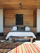 Doppelbett in sonnigem Schlafzimmer mit Holzverkleidung