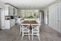 Large dining table, whit chairs and fitted cupboards in open-plan kitchen-dining room