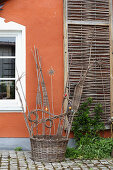 Skulptural geflochtener Weidenkorb als Deko vor dem Haus