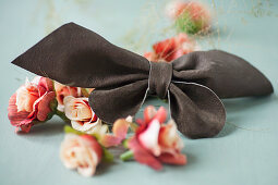 Leather bow and fabric flowers on grey surface