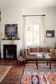 Couch neben Kamin im Wohnzimmer, gemusterter Teppich in Ethno-Look