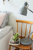 Grey lamp and small plant on old chair used as bedside table