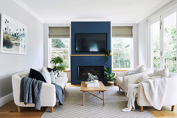Bright living room with upholstered furniture, fireplace and television on a blue wall