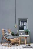 Wicker chair and plants on stone bench against grey wall