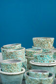Turquoise-glazed pots with structured surfaces against blue wall