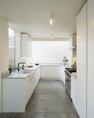 White, minimalist kitchen with rounded corner and concrete floor