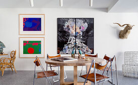 Runder Tisch aus Holz und Vintage Stühle mit Chromgestell und Leder in offenem Wohnraum mit modernen Kunstwerken an der Wand