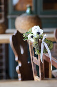 Anemones and heart-shaped wreath of ivy berries on chair backrest