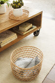 Blanket in airy basket next to wooden coffee table on castors