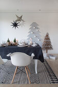 Table set for Christmas with black tablecloth in front of stylised Christmas tree on wall