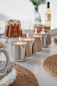Alternative Advent arrangement of candles in four tin cans in front of Advocaat cake
