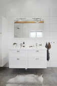White washstand below wall-mounted mirror in white bathroom