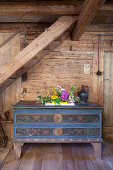 Flower arrangement on top of farmhouse trunk against wooden wall