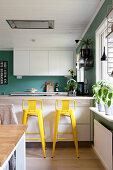 Yellow bar stools at counter in open-plan kitchen
