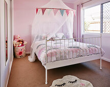 White canopy bed in pink girl's room