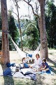 Familie beim Picknicken unter hohen Bäumen im Garten