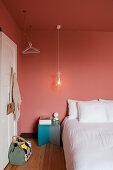 Bed with white bed linen in bedroom with salmon-pink walls