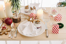 Christmas place setting with gingerbread mousse in glass bowl and guest favours in red-and-white striped boxes