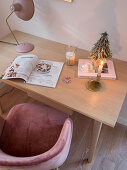 Schalenstuhl und Schreibtisch mit Weihnachtsdeko, Zeitschrift und Leuchte