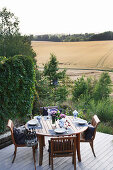 Gedeckter Tisch auf der Terrasse mit Blick auf Wald und Felder