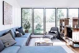 L-shaped couch with storage space and shelf as a room divider in a bright living area