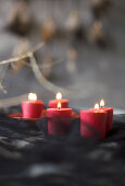 Brennende rote Kerzen vor grau-schwarzem Hintergrund