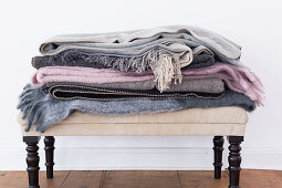 Stack of folded woollen blankets on ottoman