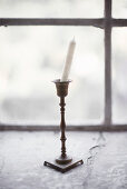 Kerze steht krumm im klassischen Kerzenhalter aus Messing