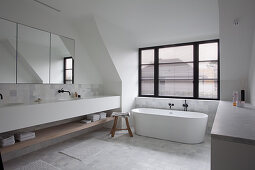 Großzügiges Badezimmer mit frei stehender Badewanne vor Fenster und Doppelwaschtisch