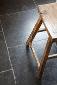 Wooden stool on black floor tiles