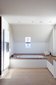 Fitted bathtub with stone surround and shelf in minimalist bathroom