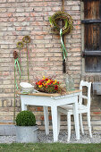 Rot-gelbes Tischgesteck mit Tulpen, Narzissen und Ranunkeln, Kränze aus Zweigen an der Wand