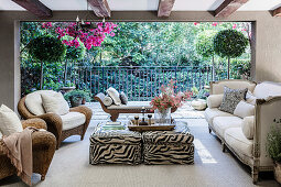 Rattan armchair, ottoman with animal print, antique sofa and day bed on living terrace