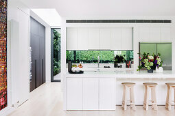 White, open kitchen with kitchen counter and bar stools