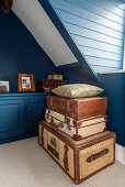 Stack of old trunks and suitcases in attic room with blue walls