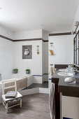 Washstand with twin sinks and bathtub in white-tiled bathroom