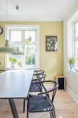 Lime-green wall and designer chairs in sunny dining room