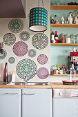 Kreisförmige Wandtattoos und Regalbretter an grüner Wand über Küchenzeile
