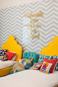Zwei gelbe Betten mit Kissen und Stofftieren, Zig-Zag-Tapete und Botschaft an der Wand