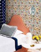 Bed with striped headboard against wall with designer wallpaper