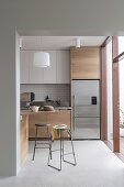 Blick in Küche, teilweise mit Holzfronten, Edelstahl-Kühlschrank und Barhockern