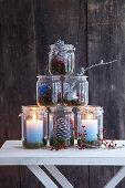 Pyramid of festive mason-jar candle lanterns decorated with natural materials